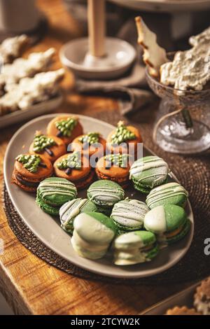 Teller mit wunderschön dekorierten Weihnachtsmakronen auf festlichem Tisch Stockfoto