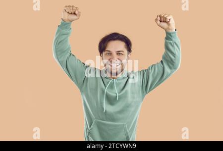 Porträt eines fröhlichen jungen Mannes, der den Sieg mit erhobenen Fäusten feiert Stockfoto