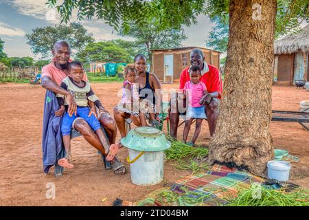 afrikanische Dorffamilie, auf dem Hof vor dem Haus, Hütte mit Strohdach im Hintergrund Stockfoto