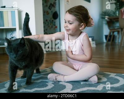 Fröhliches Kleinkind im Ballett Outfit lächelnd im Wohnzimmer Stockfoto