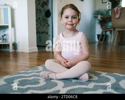 Glückliches Kleinkind im Ballett-Outfit, das im Wohnzimmer lächelt Stockfoto