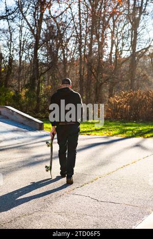 Solo-Mann-Skateboarden, die im Herbst durch einen Skatepark laufen Stockfoto