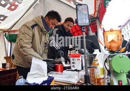 (231215) -- XIGAZE, 15. Dezember 2023 (Xinhua) -- Anbieter fördern frisch gemahlenen Kaffee über Livestreaming auf einer Messe im Kangmar County in Xigaze, südwestchinesische Autonome Region Xizang, 13. Dezember 2023. Die fünftägige Messe schloss am 14. Dezember im Kangmar County in Xigaze, das mehr als 200 freie Verkaufsstände für Händler zur Verfügung stellte. (Xinhua/Jigme Dorje) Stockfoto