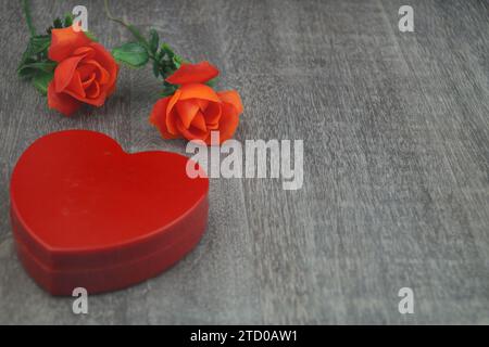 Künstliche rote Rosen mit rotem Herzschmuck Stockfoto