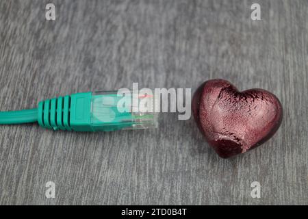 Herz mit grünem Internetkabel, symbolisches Bild der Liebe online Stockfoto