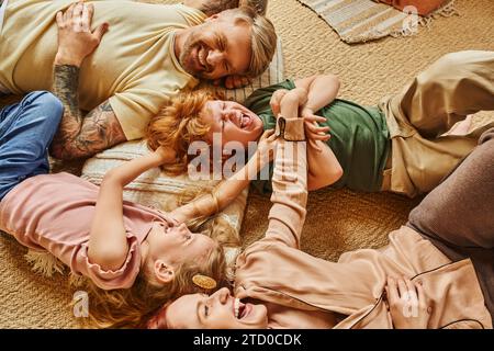 Blick auf Eltern und Kinder, die sich auf dem Boden im modernen Wohnzimmer amüsieren, schöne Momente Stockfoto