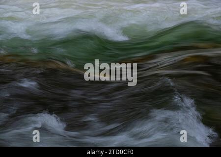 Abstrakte, unscharfe Bewegung des Wassers, das in einem Bergfluss fließt, der in den Schweizer Alpen erfasst wurde, unterstreicht die Kraft und Gelassenheit der Natur. Stockfoto