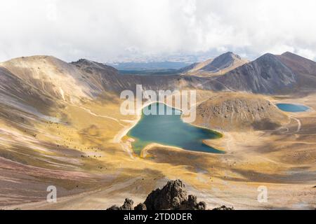 Ein Blick aus der Vogelperspektive auf die ruhigen Seen im Inneren des Vulkankraters Nevado de Toluca, mit rauem Gelände und dramatischem Himmel. Stockfoto