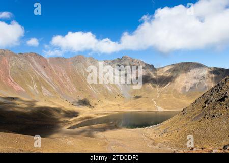 Malerischer Blick auf den ruhigen Kratersee inmitten der hohen Berge von Nevado de Toluca, Mexiko, unter einem klaren blauen Himmel. Stockfoto