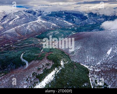 Drohnenblick auf majestätische Berge, bedeckt mit grünen Nadelbäumen und Schnee unter Wolken in der Landschaft von Neila Spanien Europa Stockfoto