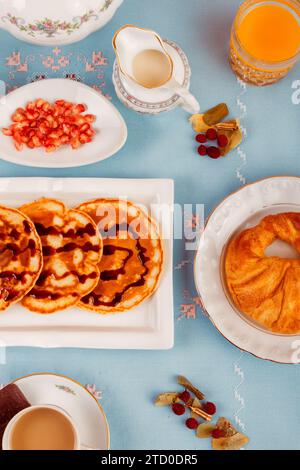 Auf einem leuchtend blauen Hintergrund gibt es eine große Auswahl an Frühstücksspeisen, darunter Waffeln, Obst und Getränke. Stockfoto