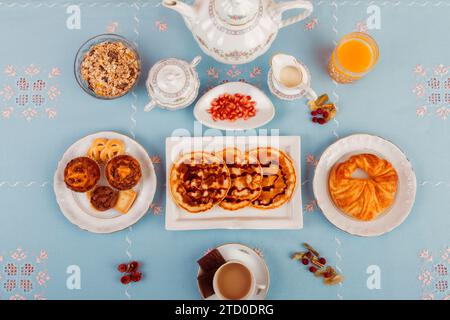 Ein kontinentales Frühstück mit Gebäck, Müsli, frischem Obst und Getränken auf blauer Oberfläche. Stockfoto