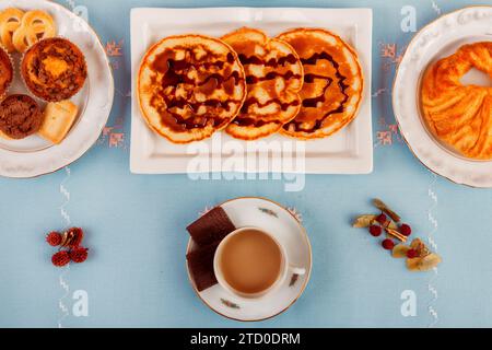 Ein kontinentales Frühstück mit Gebäck, Müsli, frischem Obst und Getränken auf blauer Oberfläche. Stockfoto