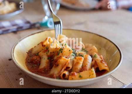 Frisch gekochte Pasta mit Gabel, serviert auf einem Holztisch im Restaurant Stockfoto