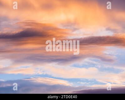 Ein atemberaubender Himmel, der während des Sonnenuntergangs mit Orangen-, Pfirsichtönen und Blautönen bemalt ist, mit weichen, ausladenden Wolkenformationen. Stockfoto