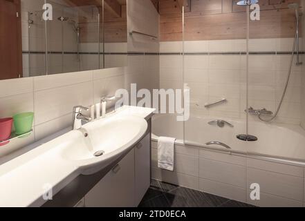 Modernes Bad mit geschwungenem Waschbecken, Badewanne und Holzelementen in einem klaren und frischen Erscheinungsbild. Stockfoto