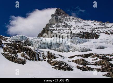 Von unten auf dem majestätischen schneebedeckten Felsberg vor dem wolkenblauen Himmel in Zermatt, Schweiz Stockfoto