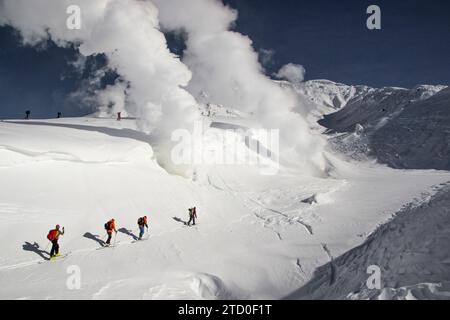 Hochwinkelansicht einer Gruppe aktiver männlicher Kletterer, die auf schneebedeckten Berghängen wandern, während sie gemeinsam Urlaub in Japan genießen Stockfoto