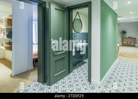 Eleganter Innenblick mit Blick auf die stilvolle Badezimmertür, die offen ist und ein modernes Waschbecken und Spiegel freigibt. Stockfoto