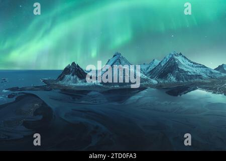 Majestätische aurora Borealis tanzt über den schneebedeckten Bergen am ruhigen Island Nachthimmel. Stockfoto