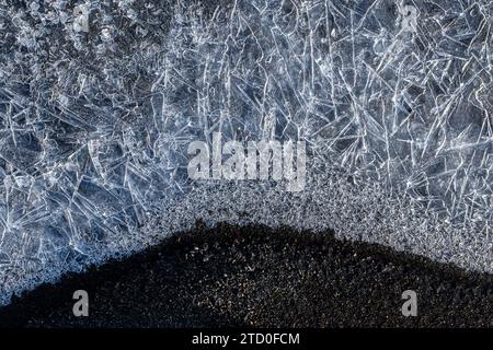 Eine detaillierte Nahaufnahme, die die natürliche Schönheit von Eiskristallen mit einer dunklen Oberfläche zeigt. Stockfoto