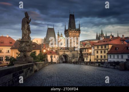 Blick am frühen Morgen auf die historische Karlsbrücke vor einem dramatischen Himmel in Prag, Tschechien, mit wunderschönen barocken Statuen. Stockfoto