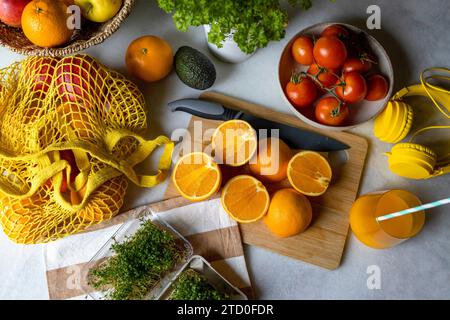 Hoher Blickwinkel von gesunden geschnittenen Orangen mit verschiedenen Gemüse und Früchten in Mesh-Tasche mit Kopfhörern auf dem Tisch zu Hause Stockfoto