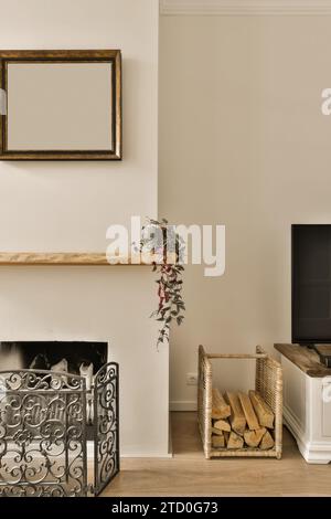 Leerer Rahmen an der Wand über Kamin durch Brennholz im Korbbehälter im Wohnzimmer montiert Stockfoto
