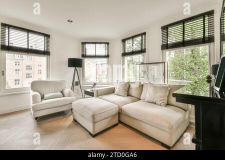 Komfortables Sofa und Kissen gegen Fenster mit Jalousien im geräumigen Wohnzimmer des modernen Apartments Stockfoto