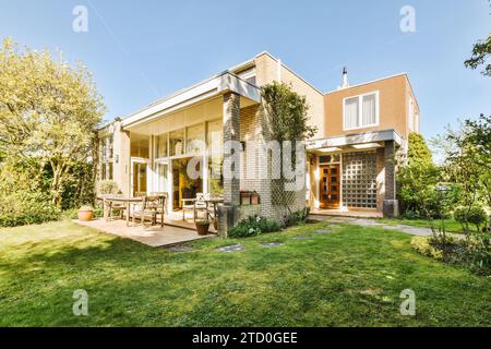 Wunderschöner Garten im Hinterhof vor einem großen modernen Backsteinhaus an sonnigem Tag vor klarem blauem Himmel Stockfoto