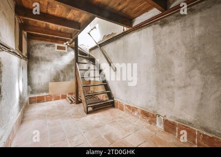 Holztreppe im verwitterten leeren Zimmer des alten Hauses mit Betonwänden und Fliesenboden Stockfoto
