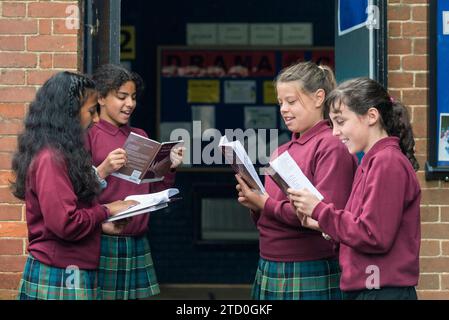 Eine Gruppe Mädchen steht vor einem Klassenzimmer und liest und probt ein Schulstück für den Theaterunterricht Stockfoto