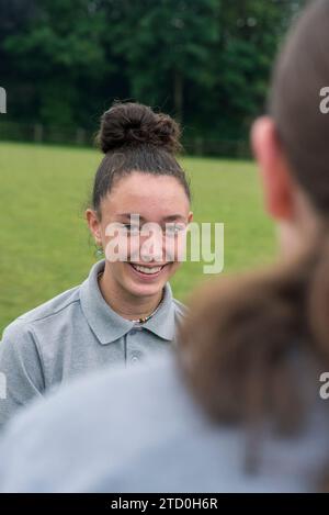 Eine Gruppe Mädchen in einer britischen High School steht draußen und spricht mit einem Lehrer und Mentor. Stockfoto