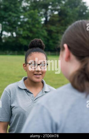 Eine Gruppe Mädchen in einer britischen High School steht draußen und spricht mit einem Lehrer und Mentor. Stockfoto