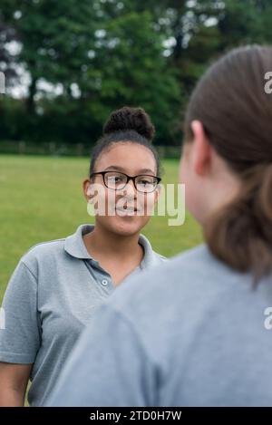 Eine Gruppe Mädchen in einer britischen High School steht draußen und spricht mit einem Lehrer und Mentor. Stockfoto