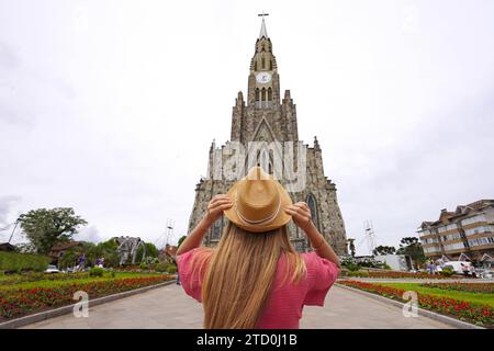 Tourismus in Canela, Brasilien. Rückansicht eines Touristenmädchens, das den Blick auf die Kirche unserer Lieben Frau von Lourdes in Canela, Rio Grande do Sul, Brasilien genießt. Stockfoto