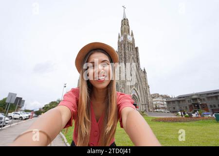 Schöne junge Frau fotografiert Selbstporträts mit der berühmten Kirche „Catedral de Pedra“ in Canela, Rio Grande do Sul, Brasilien Stockfoto