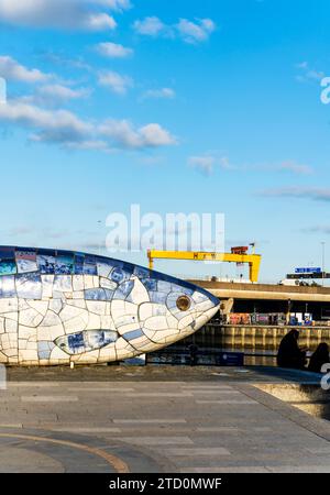 Skulptur Salmon of Knowledge oder Big Fish mit zwei gelben Schiffbau-Portalkranen Samson und Goliath entlang des Flusses Lagan, Belfast, Nordirland. Stockfoto