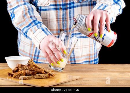 Moskau, Russland - 08. Dezember 2023: Bud-Bier aus einer Aluminiumdose in ein Glas gießen. Kopierbereich. Stockfoto