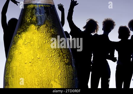 Eine taufende Flasche alkoholischer Getränke mit Silhouetten tanzender Menschen im Hintergrund Stockfoto