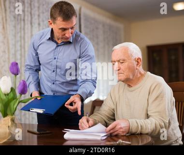 Mann, der seinem Vater beim Ausfüllen von Dokumenten hilft Stockfoto