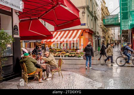 Leute, die sich an einem Tisch vor einem Café in der Rue Montorgueil im 2. Arrondissement von Paris, Frankreich, unterhalten Stockfoto