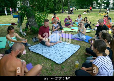 Junger Mann Musiker Mönch spielt indisches Schlaginstrument Mridangam für Meditation, Gruppe von Leuten hört zu. Juli 2020. Kiew, Ukraine Stockfoto