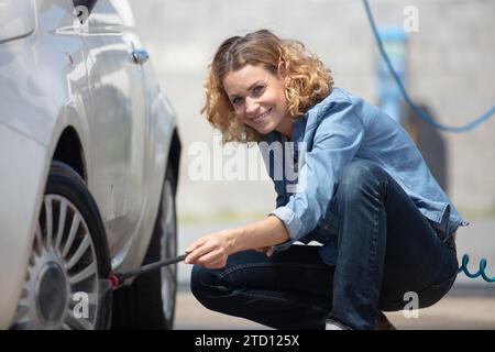 Eine junge Frau, die den Reifendruck überprüft Stockfoto