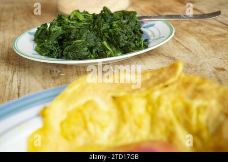 Spinatschale mit Omelette im Vordergrund Stockfoto