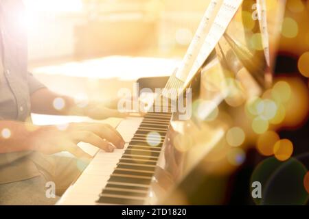 Weihnachtsmusik und Neujahrsmusik. Mann spielt drinnen Klavier, Nahaufnahme. Bokeh-Effekt Stockfoto