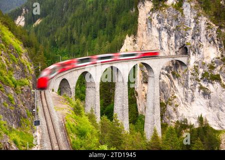 Schweizer Roter Zug auf Viadukt in den Bergen für eine malerische Fahrt Stockfoto