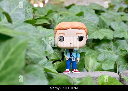 Funko Pop Actionfigur von Max Mayfield mit Kassettenspieler aus der Netflix TV-Serie Stranger Things. Grüne Efeublätter, verlassener Garten. Stockfoto