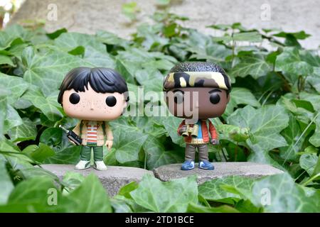 Funko Pop Actionfiguren von Mike und Lucas aus der Netflix TV-Serie Stranger Things. Grüne Efeupflanzen, verlassener Garten, Abenteuer, Freundschaft. Stockfoto