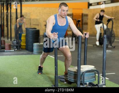 Motivierter starker Mann mittleren Alters in Activewear Cross Fit Ausrüstung auf Kunstrasen im Fitnessstudio. CrossFit Healthy Konzept Stockfoto